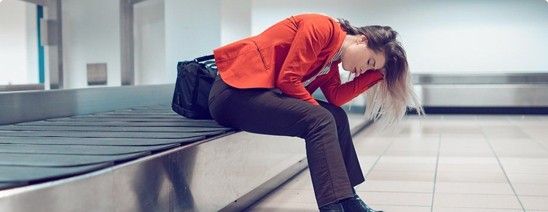 Viajera esperando su maleta en la cinta de equipaje del aeropuerto